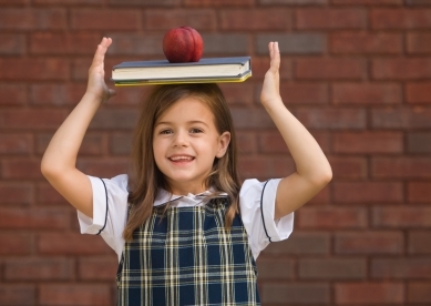 Young girl balancing school book on her head